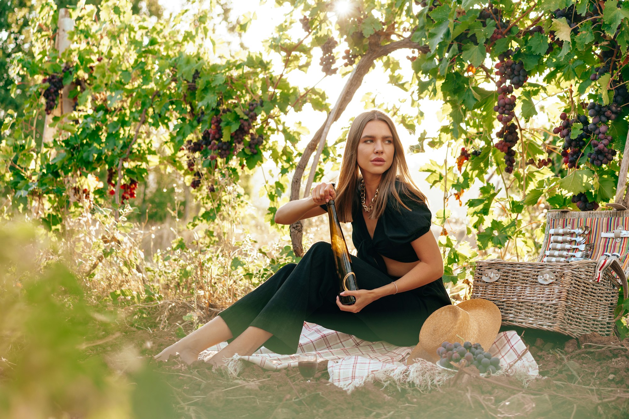 Young blonde woman sitting on a picnic in a vineyard Young blonde woman sitting on a picnic in a vineyard