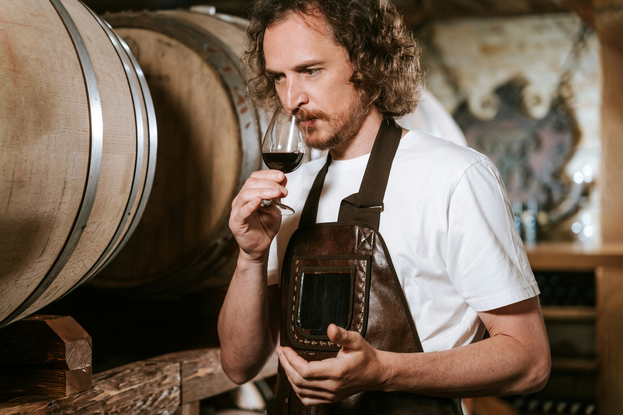 Winemaker tasting wine in a cellar with wooden barrels Winemaker tasting wine in a cellar with wooden barrels