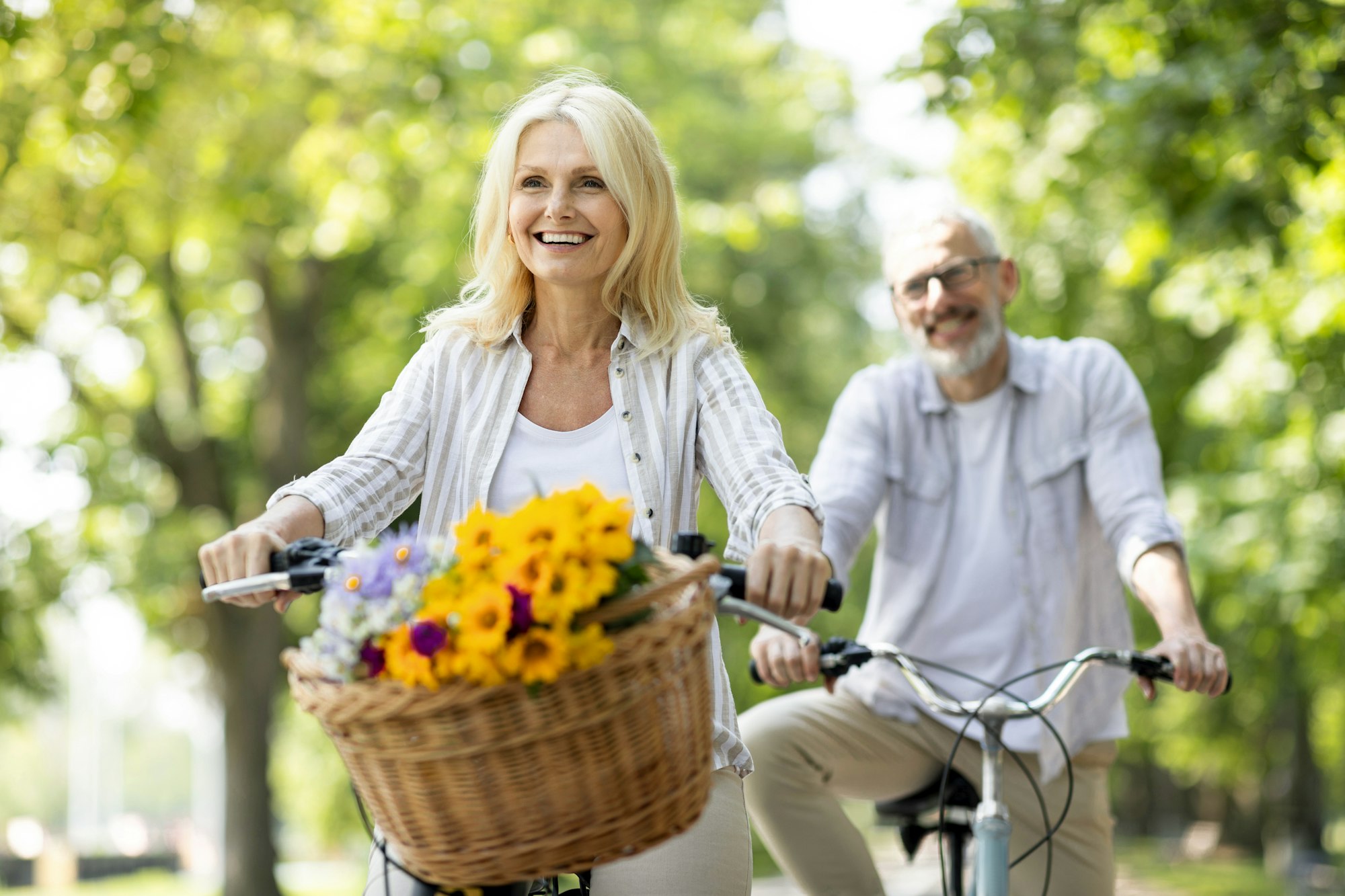Active Retirement. Beautiful Senior Woman Riding Bycicles With Her Husband In Park Active Retirement. Beautiful Senior Woman Riding Bycicles With Her Husband In Park