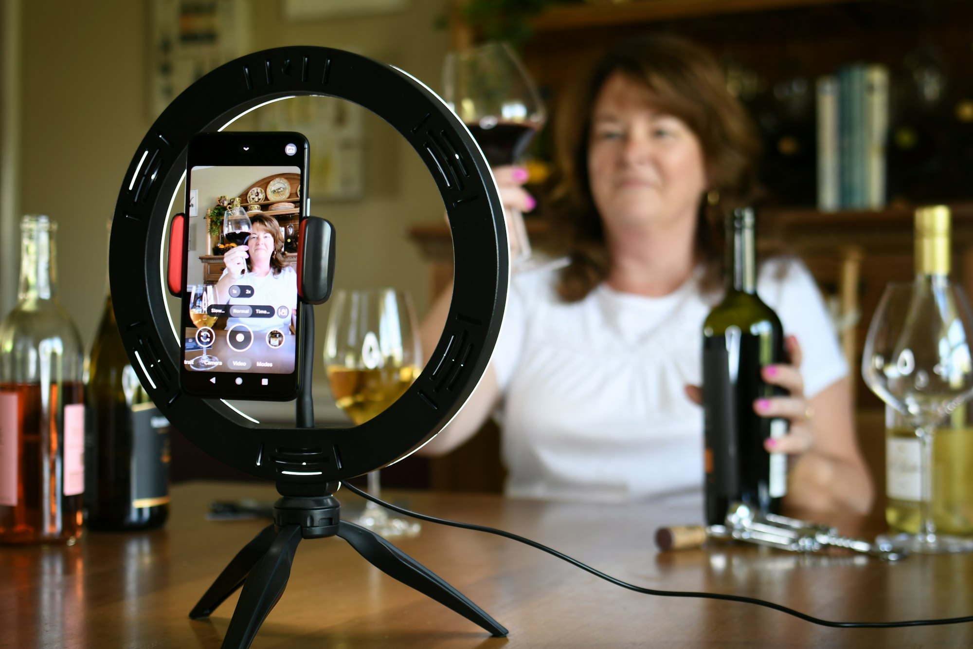 Female leading virtual wine tasting online video social media or live stream with light ring & phone